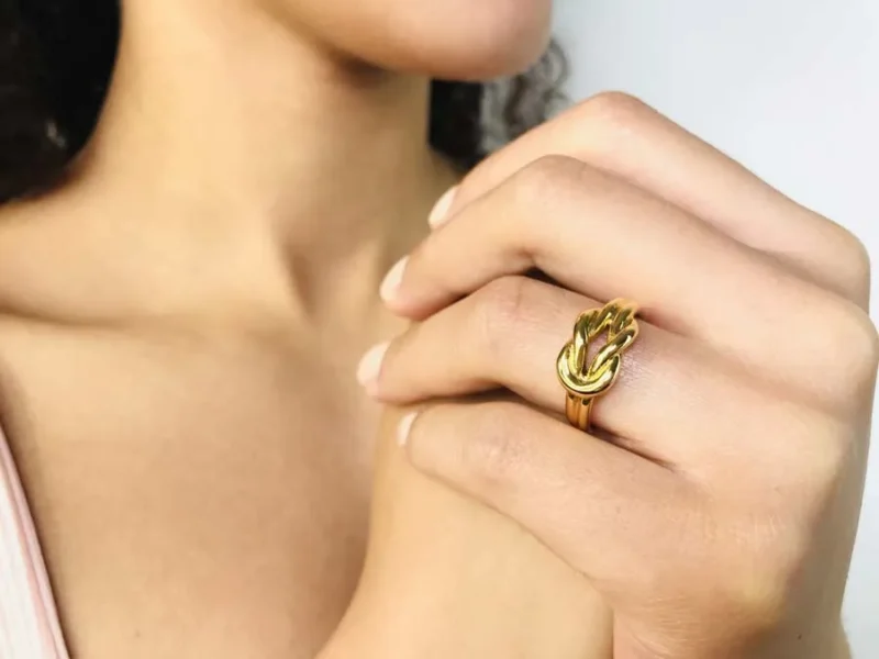 Doigt pourtant bague or avec noeud sur le sommet de l'anneau